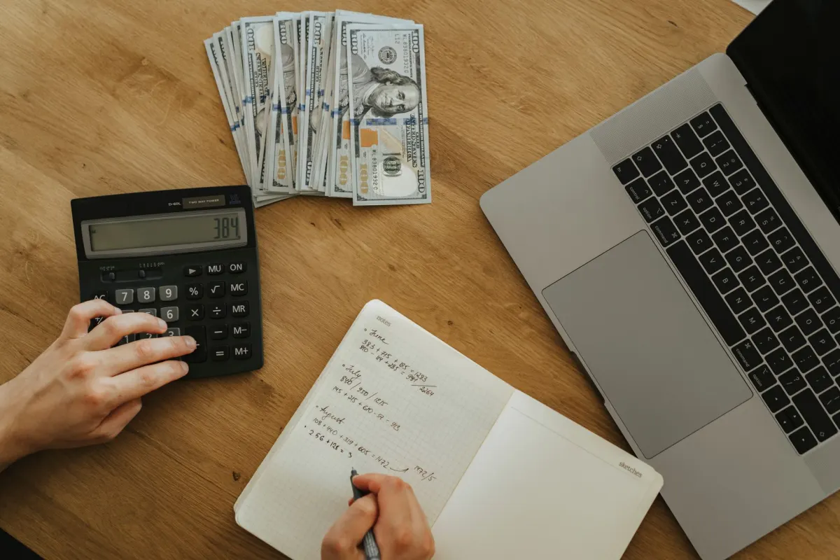 A hand works out numbers with a calculator and notebook, matching the section that walks through calculating a self-promotion ratio.