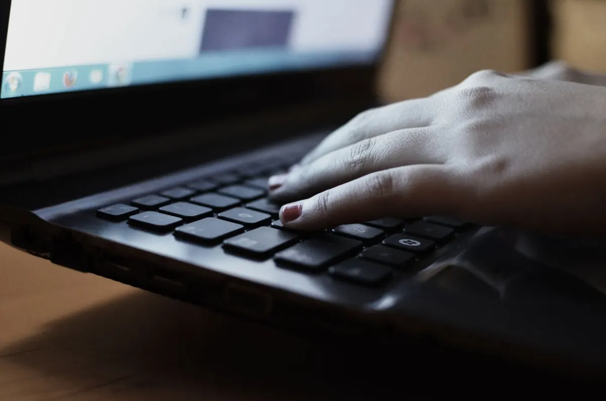 Gros plan sur des mains tapant sur un clavier d'ordinateur portable, évoquant les conversations non filtrées de Reddit.