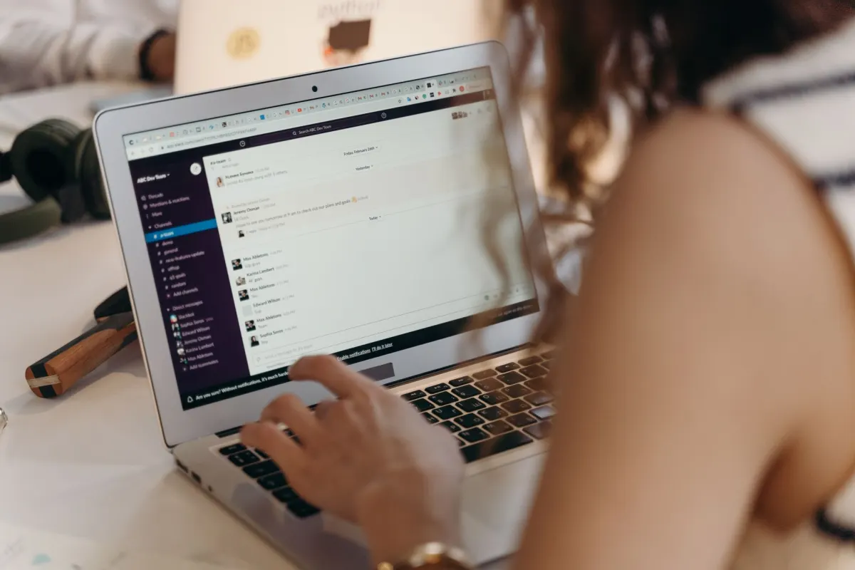 A woman typing an email on a laptop, the way you would write a short request asking a writer to add a link.