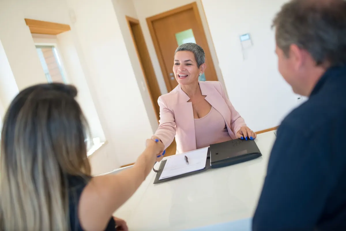 Two people shaking hands across a table after signing a deal, the moment Zap 4 starts monitoring a new client's site.